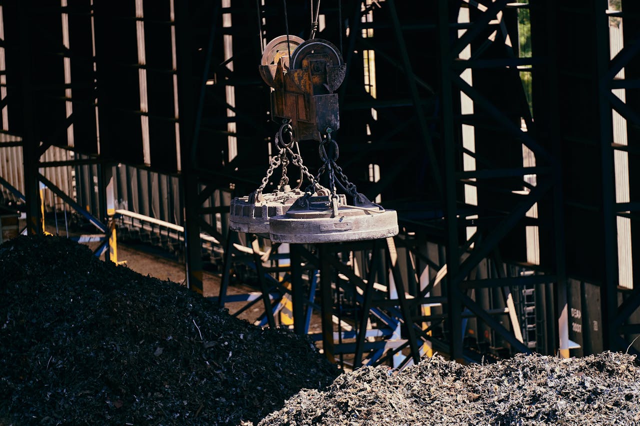İzmir Hurdacı Overhead view of industrial magnet lifting scrap metal in recycling plant.